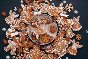 Christmas hand-painted gingerbread with icing and cookie box on black background, view from above. Holiday food, homemade baking, Christmas and New Year traditions. - 383776398