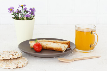 Homemade pancakes filled with cottage cheese on a plate and a cup of tea
