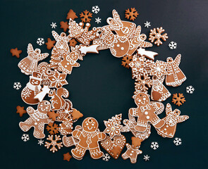 Christmas wreath made from gingerbread cookies with icing and confectionery mastic snowflakes on black background with space for text. Holiday food, homemade baking, Christmas and New Year traditions. - 383776729