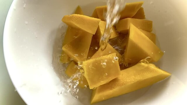 Pouring water on yellow pumpkin pieces for the Halloween cooking season