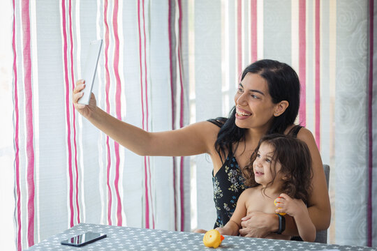 mother and daughter use tablet in the dining room at home.