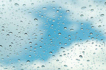Raindrop on car window glass in morning rainy season for background or wallpaper. Drop of water on glass with blue sky and clouds.