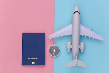 Minimalism travel, adventure flat lay. Compass and passport, air plane on blue-pink pastel background. Top view