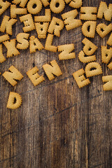 Top view photo of many alphabet cookies on a brown wooden background.
