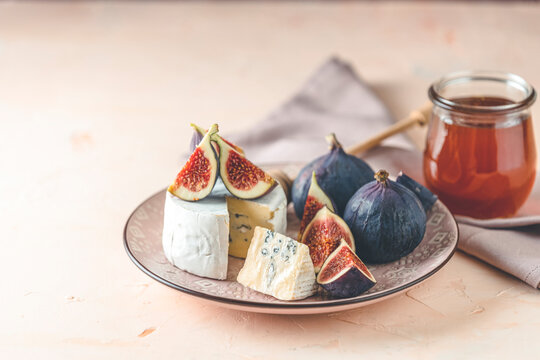 Blue or bleu cheese with fig and honey or maple syrup on pink plate. Tasty white cheese close up view