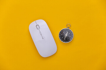 Compass and pc mouse on yellow background. Online business or travel. Top view