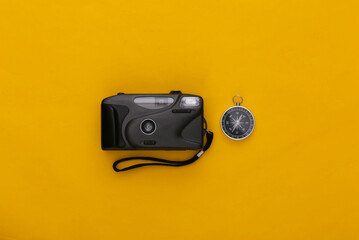 Compass and camera on a yellow background. Top view. Minimalism travel concept. Flat lay