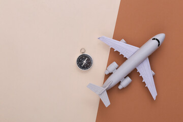 Minimalism travel flat lay. Compass and air plane on beige brown background. Top view