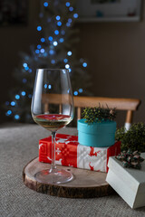 Party gift box and glasses of white wine with defocused Christmas tree lights. Christmas at home