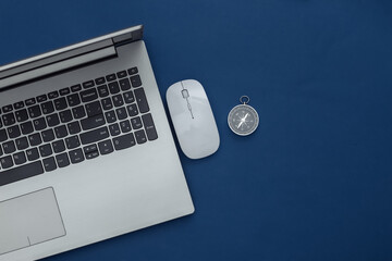 Laptop, pc mouse and compass on classic blue background. Online business or travel. Top view