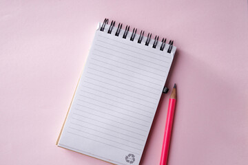 Pink memo note pad and pink colored pencil on pink background.