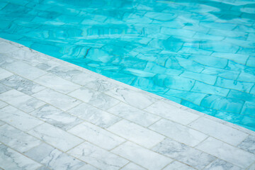 Fototapeta na wymiar Luxury swimming pool which is built from white marble rock material, full filled with clearly blue water. Background and object photo.