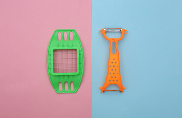 Kitchen tool for cutting vegetables and knife for peeling skin on blue pink background. Top view