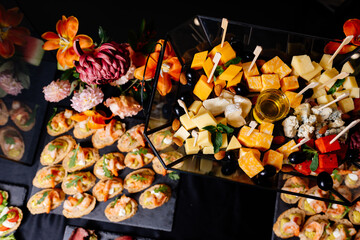 Cheese platter with different varieties and various bruschetta on black table