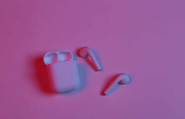 Wireless headphones with charging case in neon red blue neon light.