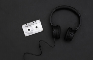 Retro audio cassette and headphones on a black background. Top view