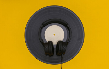 Retro vinyl record and stereo headphones on yellow background. Top view
