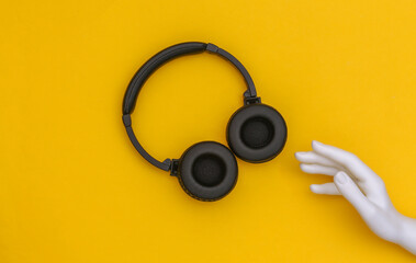 The mannequin's white hand touches headphones on yellow background. Top view