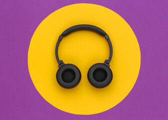 Wireless stereo headphones on a purple background with a yellow circle. Top view