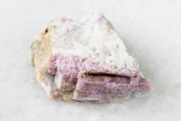 macro photography of sample of natural mineral from geological collection - raw pink Tourmaline mineral in feldspar and quartz rock from Kalba Range, Kazakhstan on white marble background