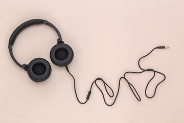 Stereo headphones with cable on a beige background. Top view