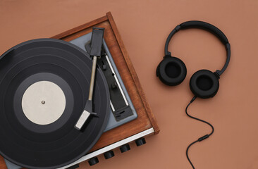 Retro vinyl player and stereo headphones on a brown background. Top view. Flat lay