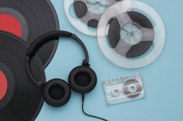 Retro vinyl records, audio magnetic reel, audio cassette and stereo headphones on a blue background. Top view. Flat lay