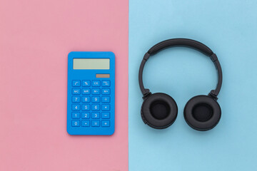 Calculator with headphones on a blue pink pastel background. Top view