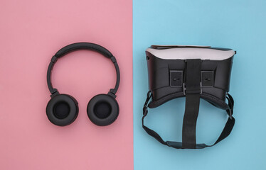 Flat lay composition of modern gadgets. Vr helmet, headphones on pink blue background. Top view