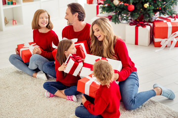 Obraz na płótnie Canvas Portrait of nice attractive big full cheerful adorable family sitting on floor exchanging giftboxes Eve Noel December newyear having fun in light white apartment house indoor