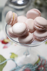 rose gold dusty pink filled macaroon served in a large glass vase on a white table with floral table cloth 