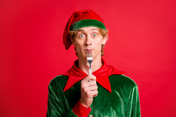 Photo of funky elf guy lick fork x-mas christmas spirit meal concept wear green headwear isolated...