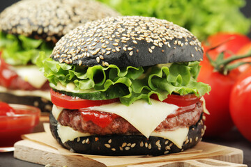 A black burger with vegetables and beef meat