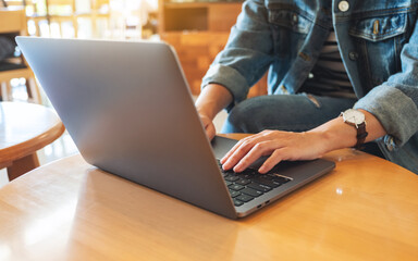 Closeup image of a woman working and typing on laptop computer keyboard on the table