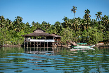 Obraz premium A simple wooden house by the turquoise riverside, Ngwesaung, Myanmar