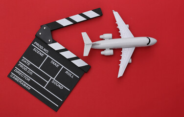 Film clapper board and air plane on red background. Cinema industry, entertainment. Top view