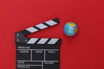 Film clapper board and globe on red background. Cinema industry, entertainment. Top view