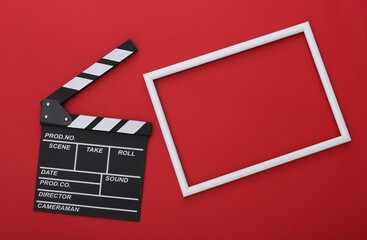 Fototapeta na wymiar Film clapper board with white frame for copy space on red background. Cinema industry, entertainment. Top view