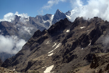 Mountain landscape with glaciers and clouds. View from the Koshtan mountain pass (3513 meters above sea level). Caucasus, Russia.