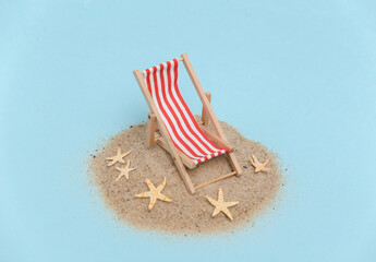 Fototapeta na wymiar Summer beach travel vacation concept. Mini beach deck chair on island with sand and starfish