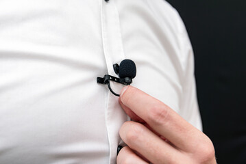 A man dressing in white shirt holding small lavalier microphone 