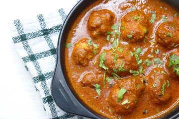 Indian cuisine - Kashmiri Dum Aloo or Potatoes in red gravy over white background. Garnished with...