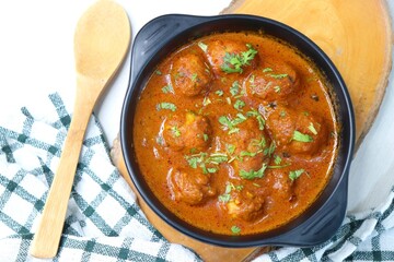 Indian cuisine - Kashmiri Dum Aloo or Potatoes in red gravy over white background. Garnished with...