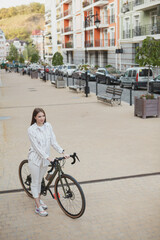 Fototapeta premium Vertical top view shot of a female cyclist standing on the street, looking around, copy space