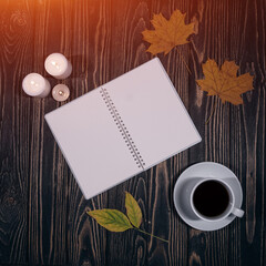 top view of empty notepad, cup of coffee and fall leaves on wooden background