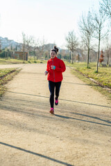 Front view of a fitness girl training running in the morning park