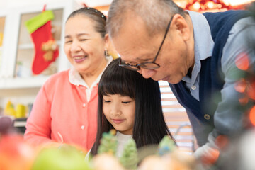 Long hair long hair with bangs Asian lovely girl smile happily to be able to make a Christmas tree shaped cupcakes together with her grandparents on Christmas. Also make grandparents happy.