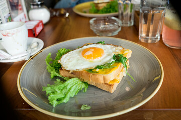 Healthy protein breakfast - crispy toasted bread with fried egg, bacon and fresh lettuce and cherry tomato