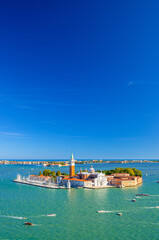 Fototapeta na wymiar San Giorgio Maggiore island with Campanile San Giorgio in Venetian Lagoon, sailing boats in St. Mark Basin, Lido island, blue sky background, vertical view, Venice city, Veneto region, Italy.