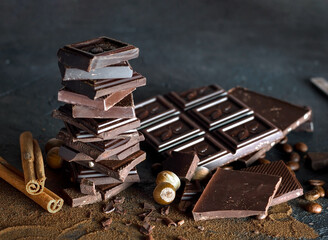 Composition of bars and pieces of different milk and dark chocolate, grated cocoa on a brown...